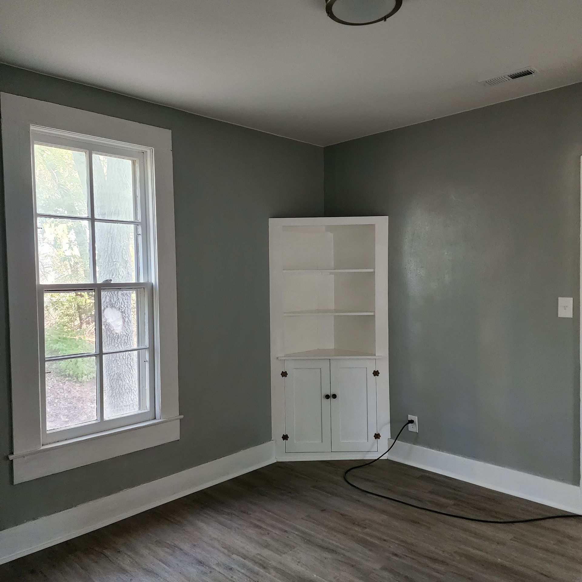Small Dining room after professional remodel, with freshly painted wood trim, accents, and wall, and new flooring.
