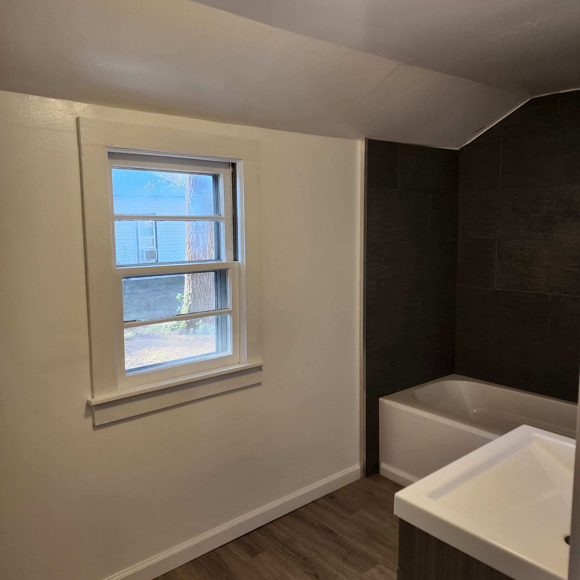 Small Bathroom Remodel with sloped ceiling above newly refinished bathtub and sink