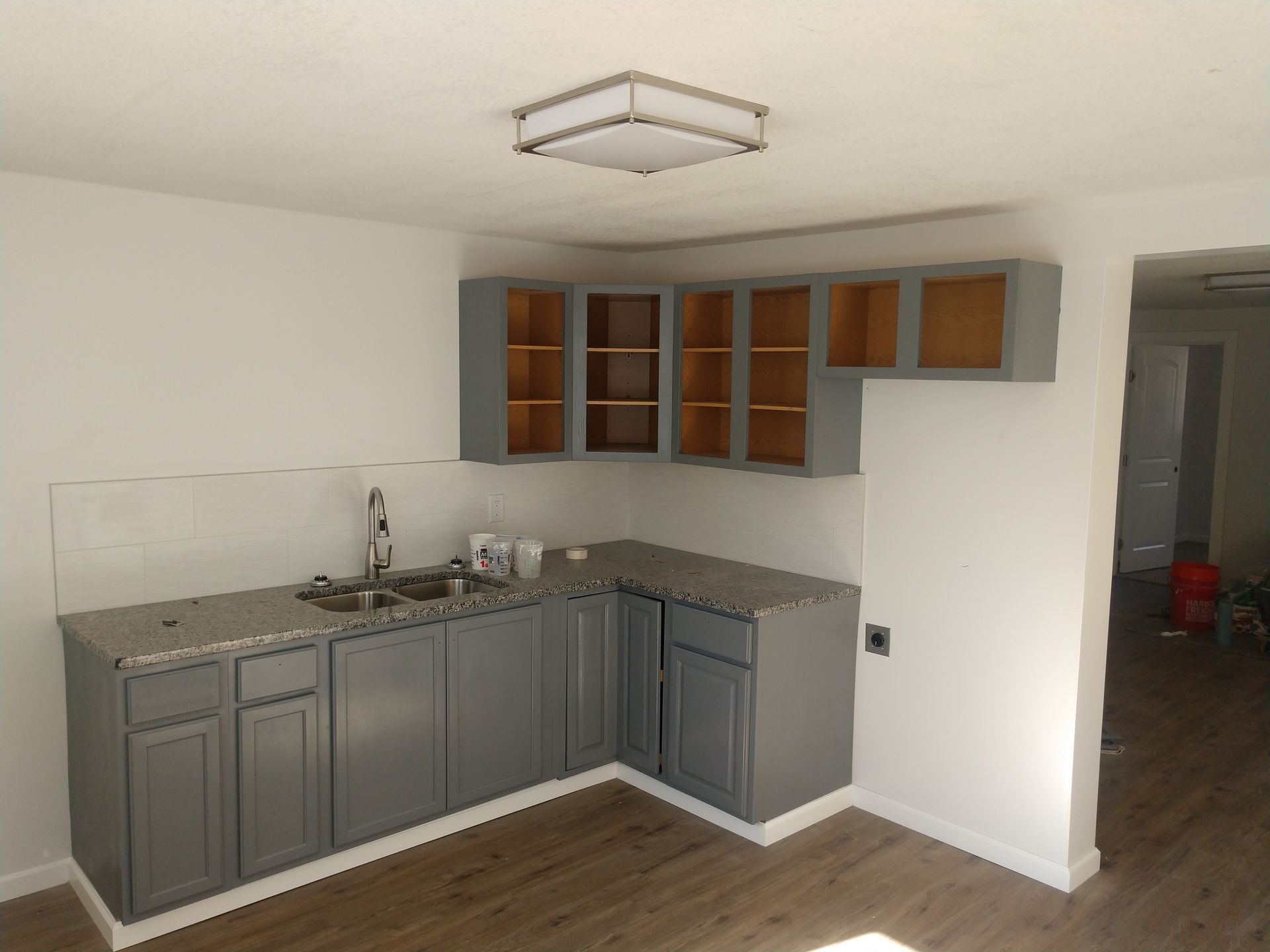 Kitchen remodeled to have freshly painted white walls and grey cabinetry