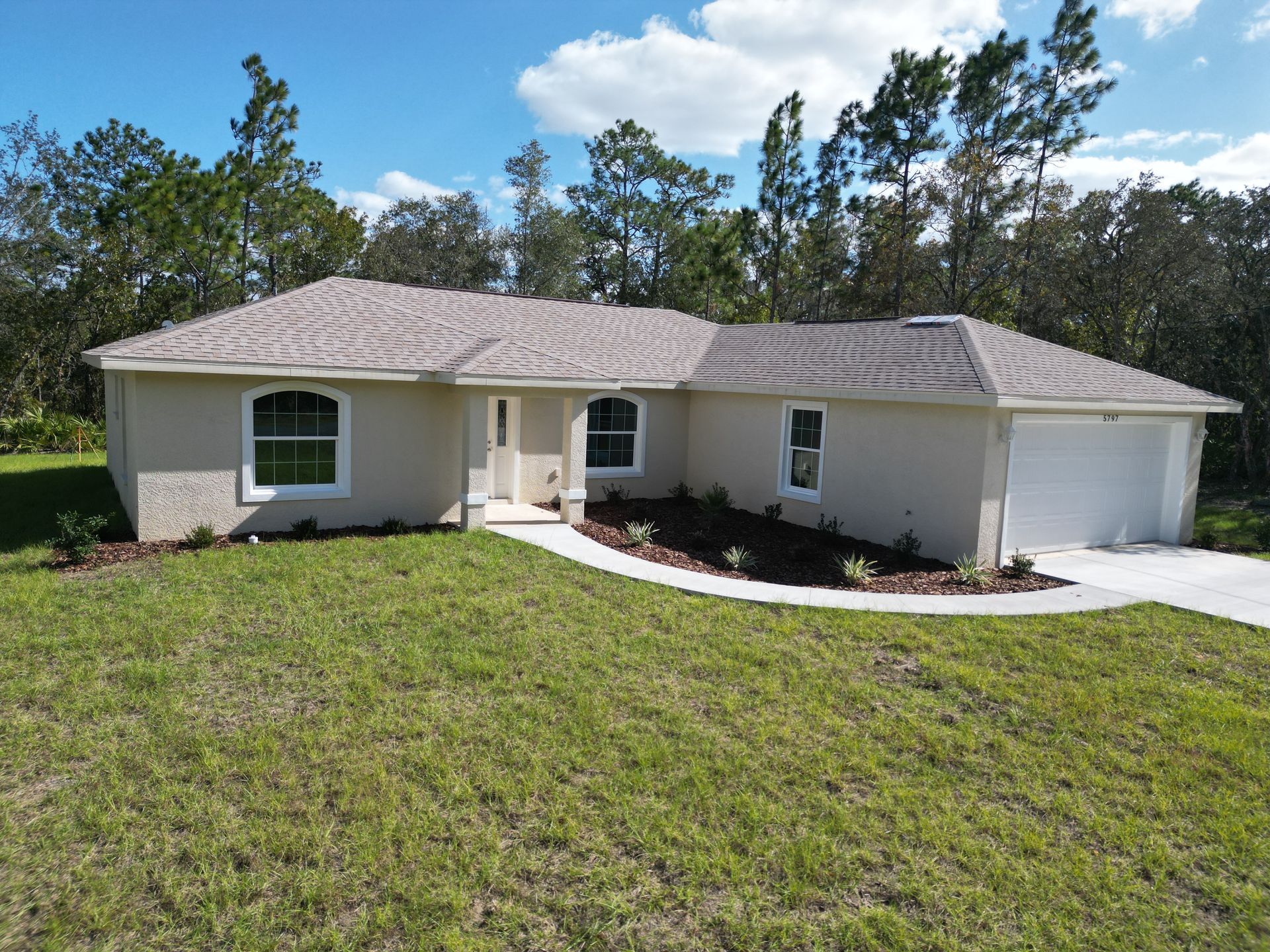Beige suburban home with landscaped yard and driveway.