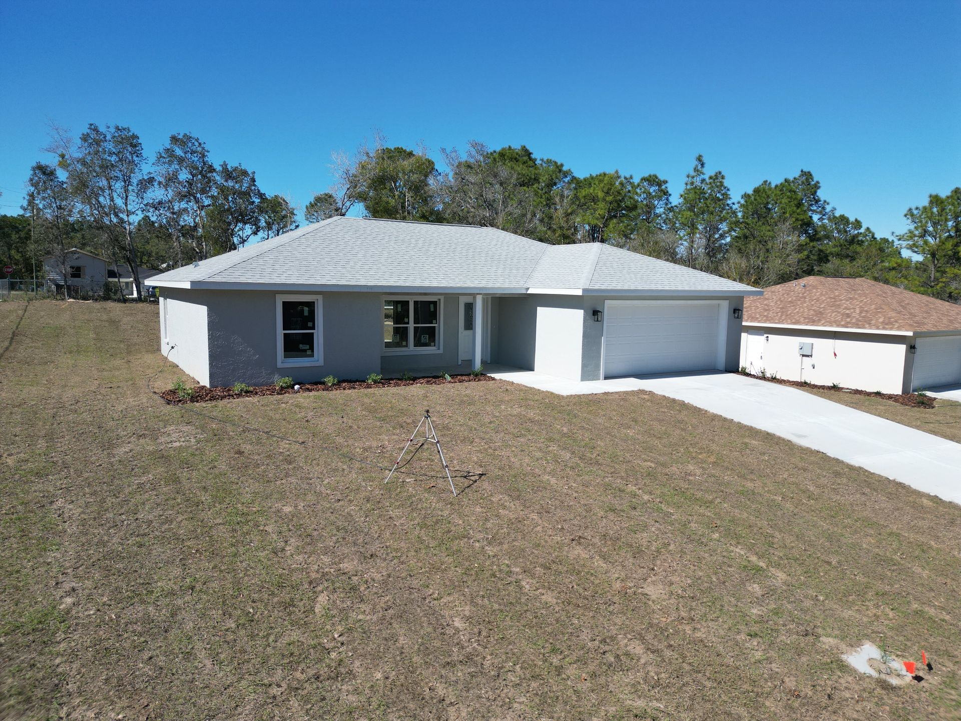 New light gray house with a two-car garage, on a grassy lot under a blue sky.