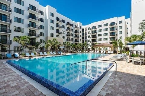 A large swimming pool in front of a large apartment building built by Into h2o Pools & Spas Cape Coral