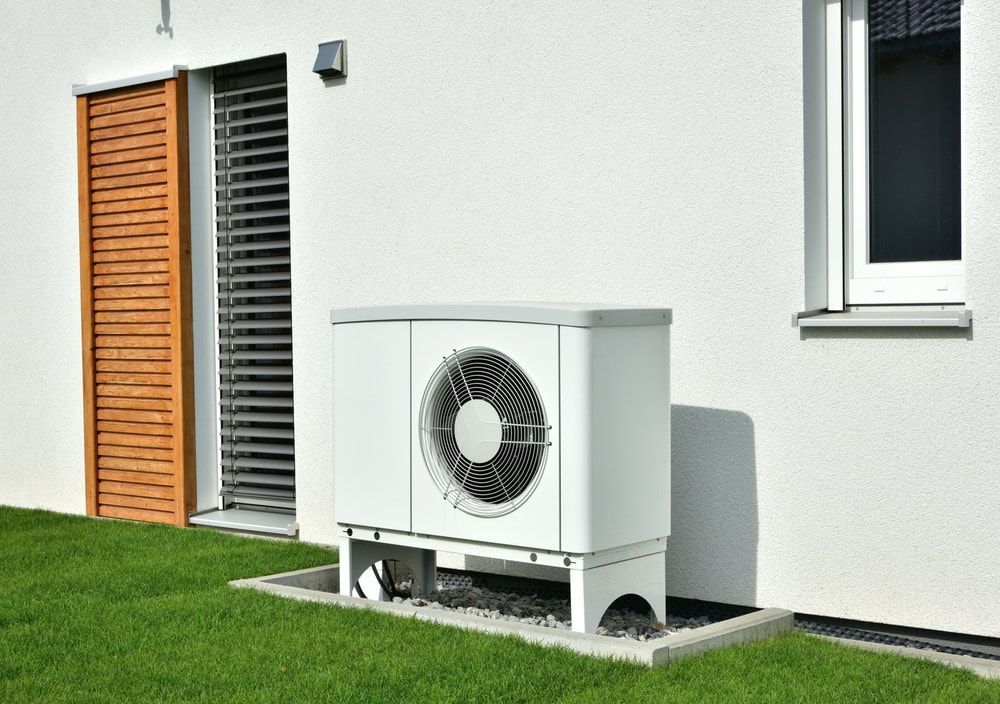 White Heat Pump Unit Next to a House on Green Grass — Frosty Solutions Air Conditioning In Mudgee, NSW