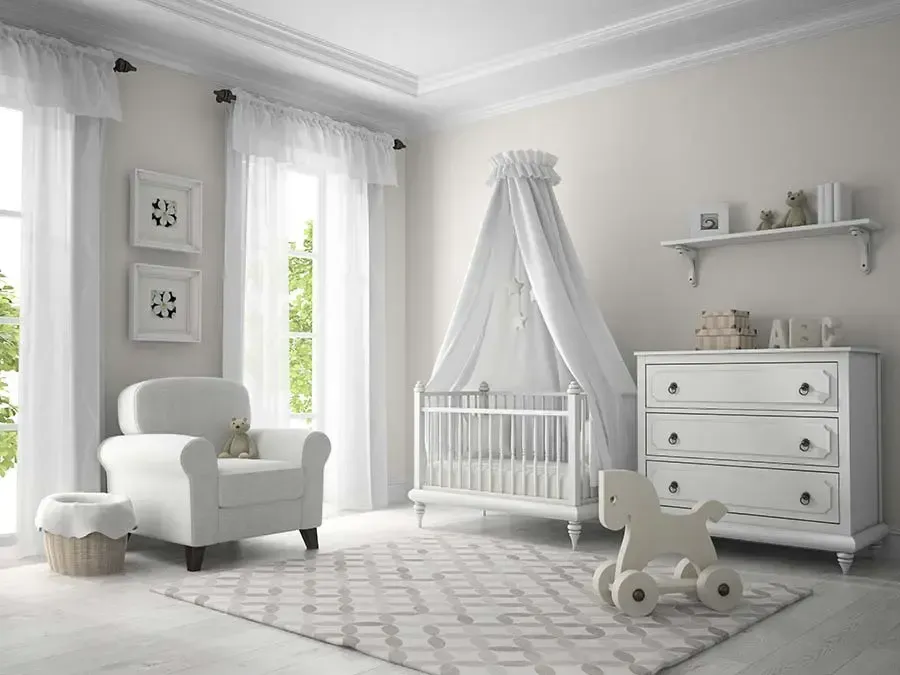 White nursery with crib, armchair, dresser, rocking horse, and patterned rug.
