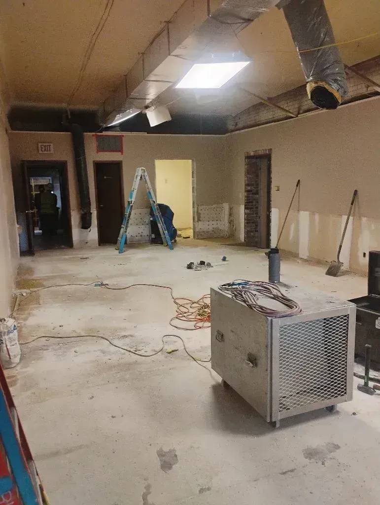Renovated room with ladders, tools, exposed ceiling ducts, and a portable heater on the floor