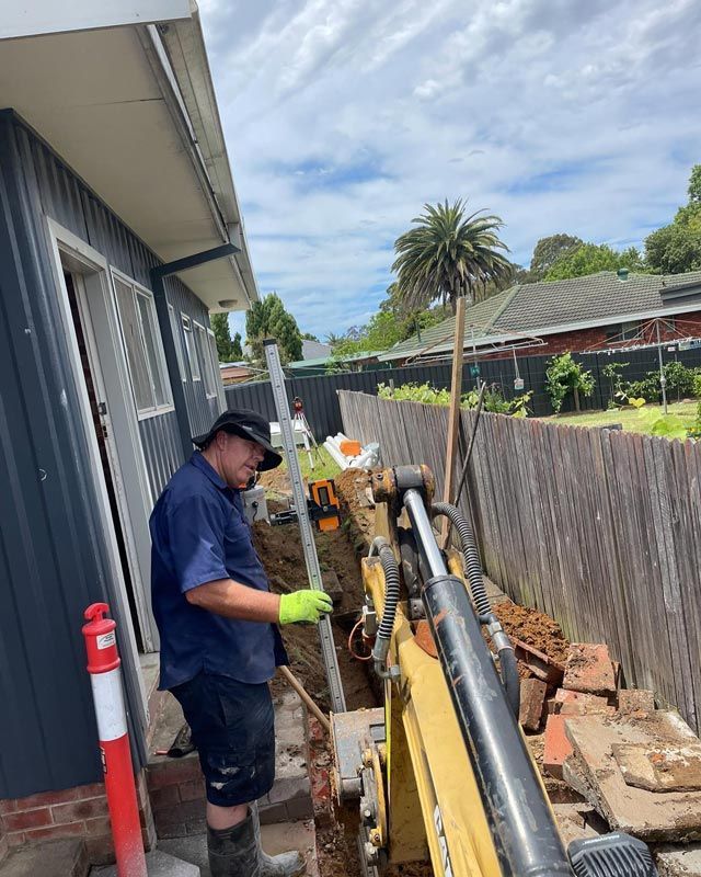 A Man Wearing Cap And Measuring the Depth Of Ground — Bridge Plumbing & Trades in Nowra, NSW