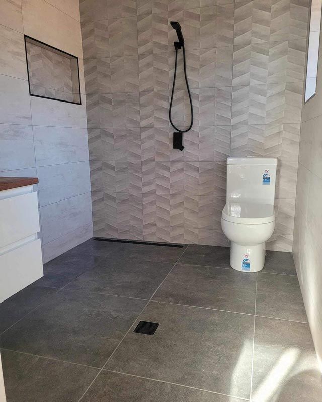 A Clean Washroom With A Closed Toilet Seat — Bridge Plumbing & Trades in Nowra, NSW