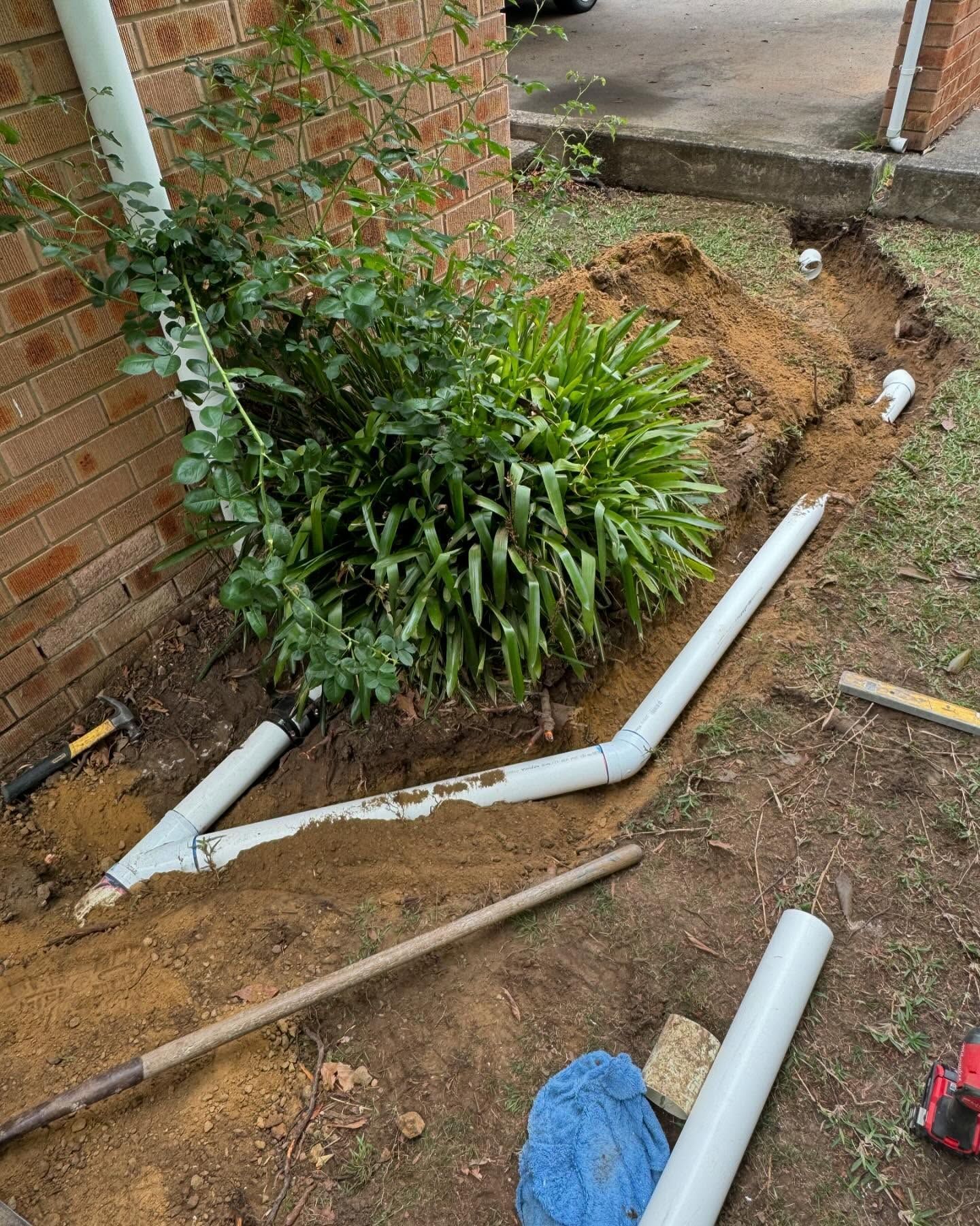 A Trench Dug in Dirt Next to a Brick Building — Bridge Plumbing & Trades In Gerringong, NSW