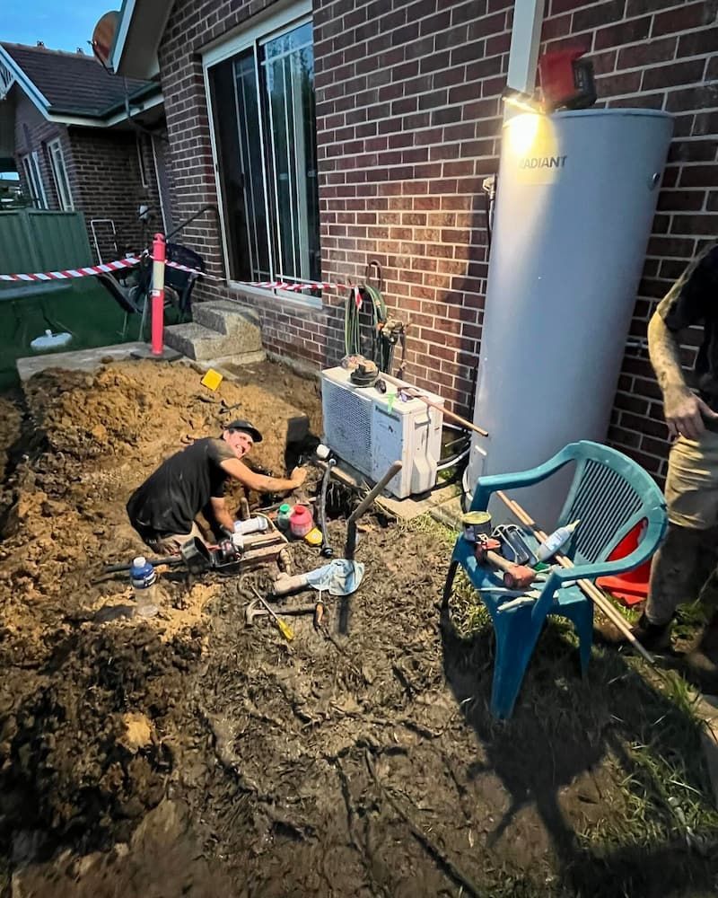 Plumber Repairing Underground Pipe In Excavated Trench Outside House In Nowra