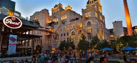 The Pearl district in San Antonio, Texas, features a historic brick building, industrial smokestack, and evening crowd.