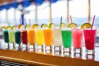 Colorful cocktails in shot glasses lined up on a bar, each topped with a straw and lime slice