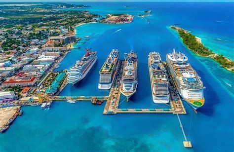 Aerial view of a tropical cruise port with multiple docked ships in turquoise water and a coastal town