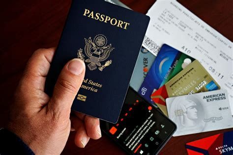 Hand holding a passport beside scattered credit cards and travel documents on a table