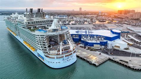 Large cruise ship docked at a snowy port beside a blue terminal at sunset