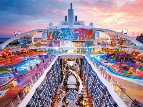 Colorful futuristic resort deck at sunset with pools, palm trees, and a central walkway under arched structures