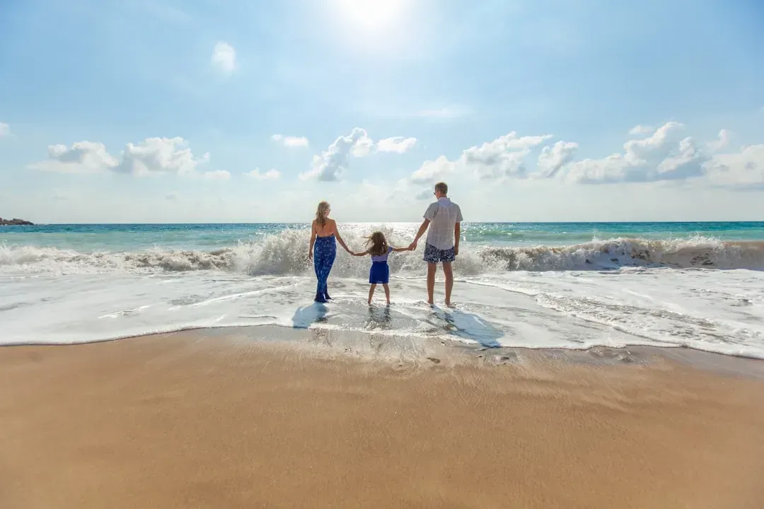 A family is walking on the beach holding hands.