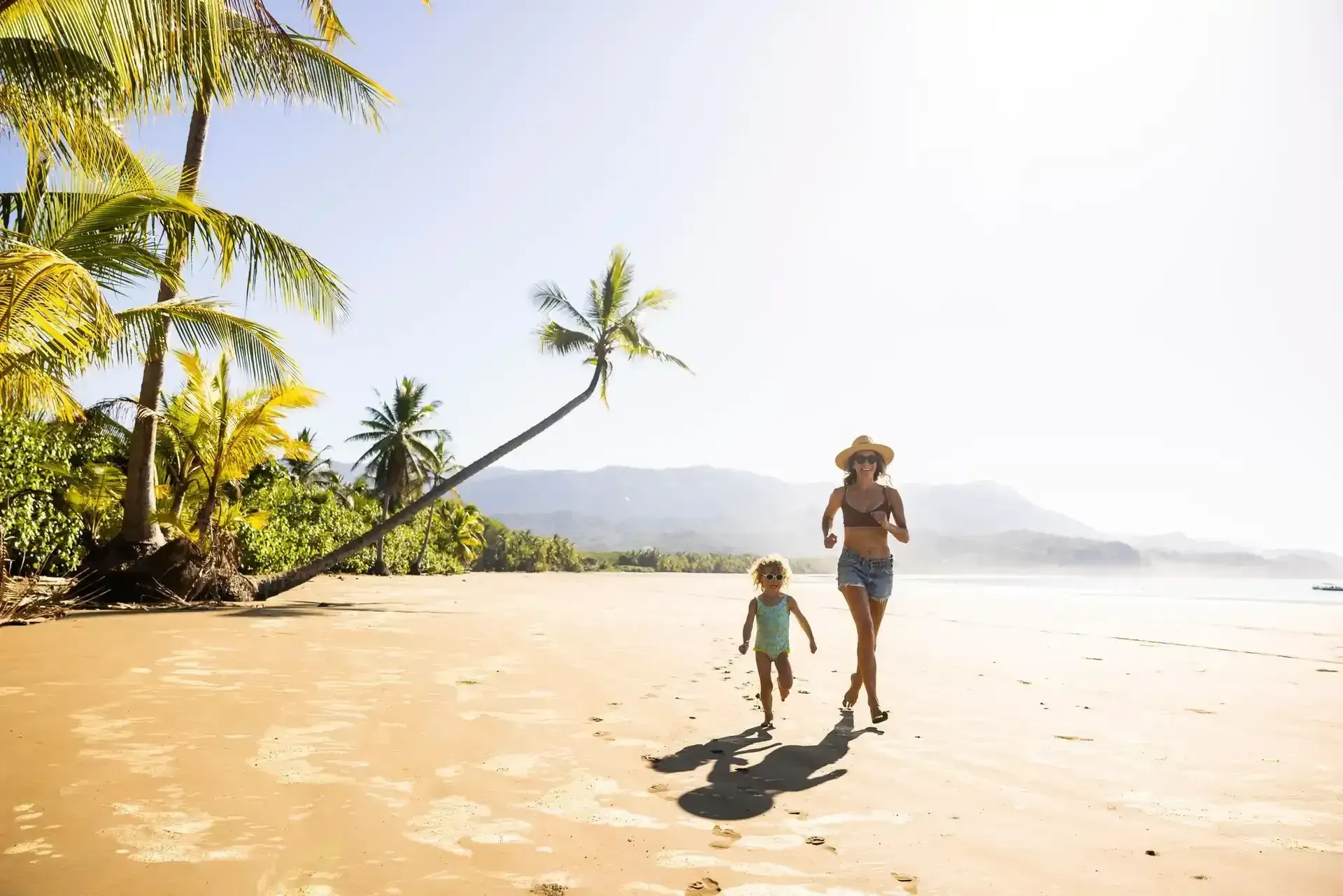 A woman and a child are running on the beach.