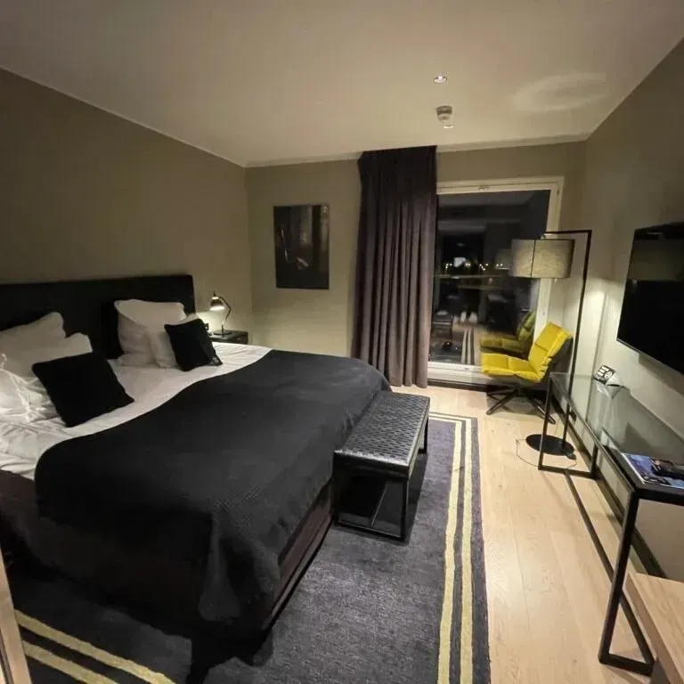 A hotel room with a king size bed and a yellow chair