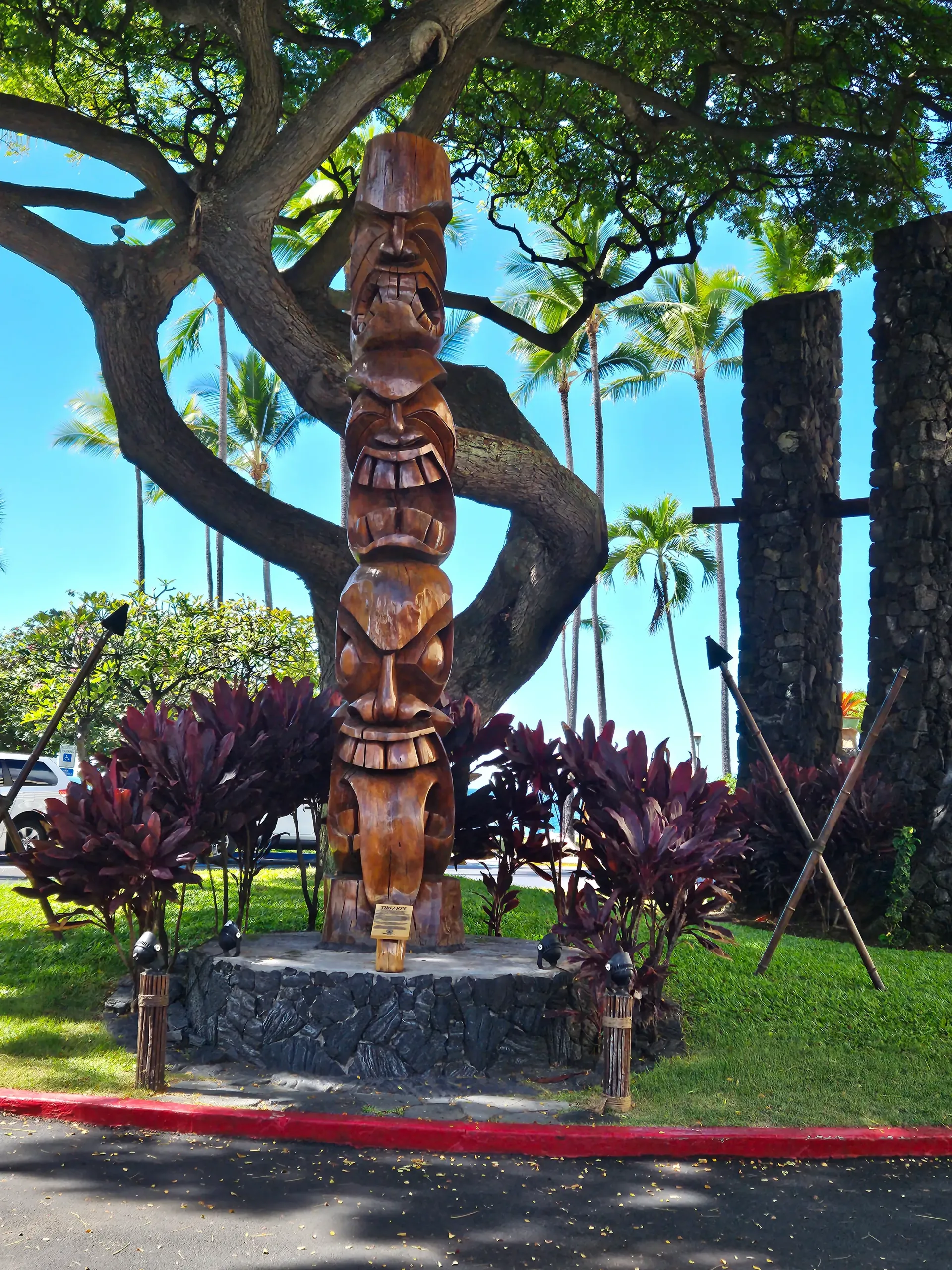 A totem pole in a park with a tree in the background