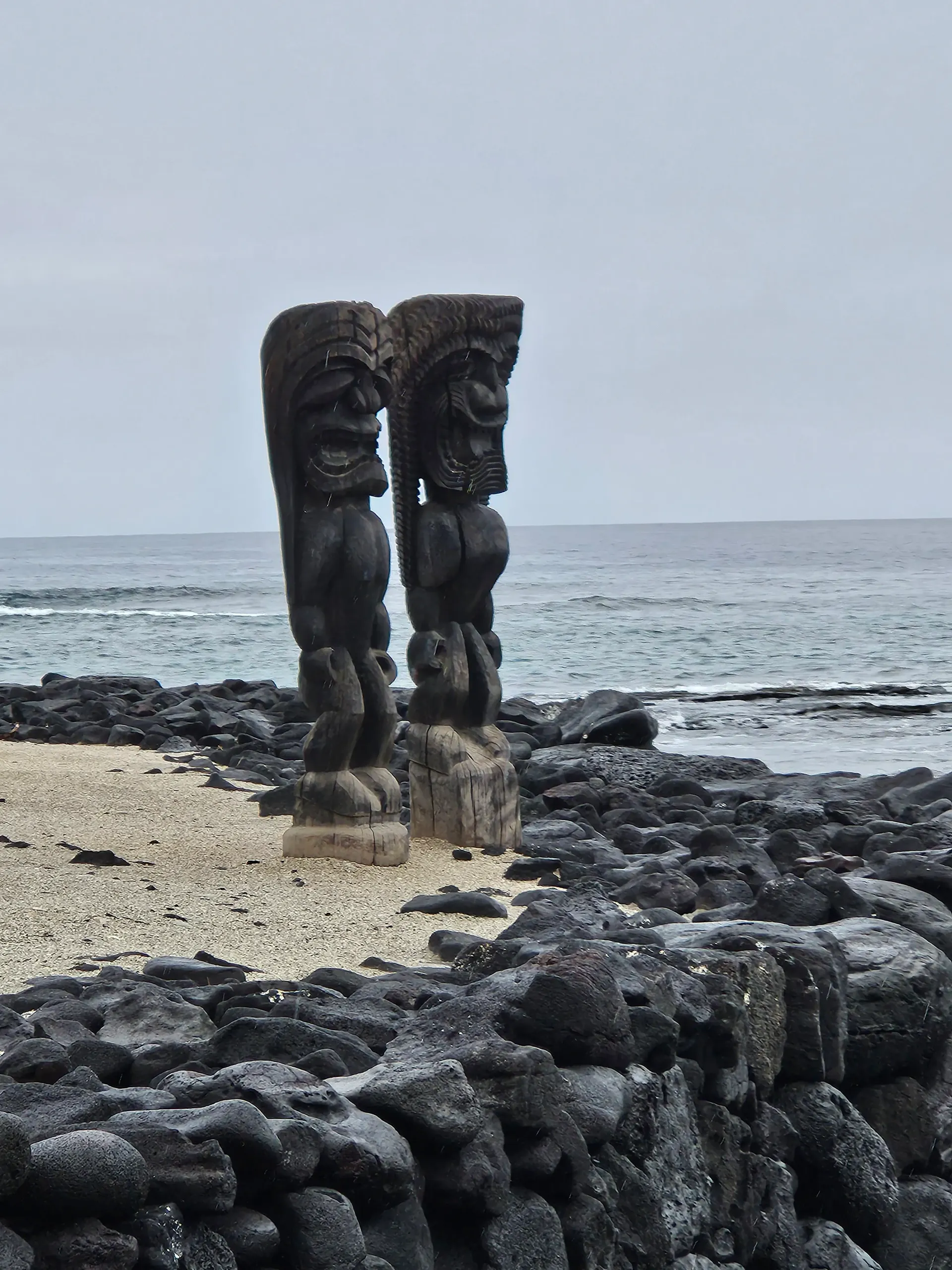 Two statues on a rocky beach near the ocean