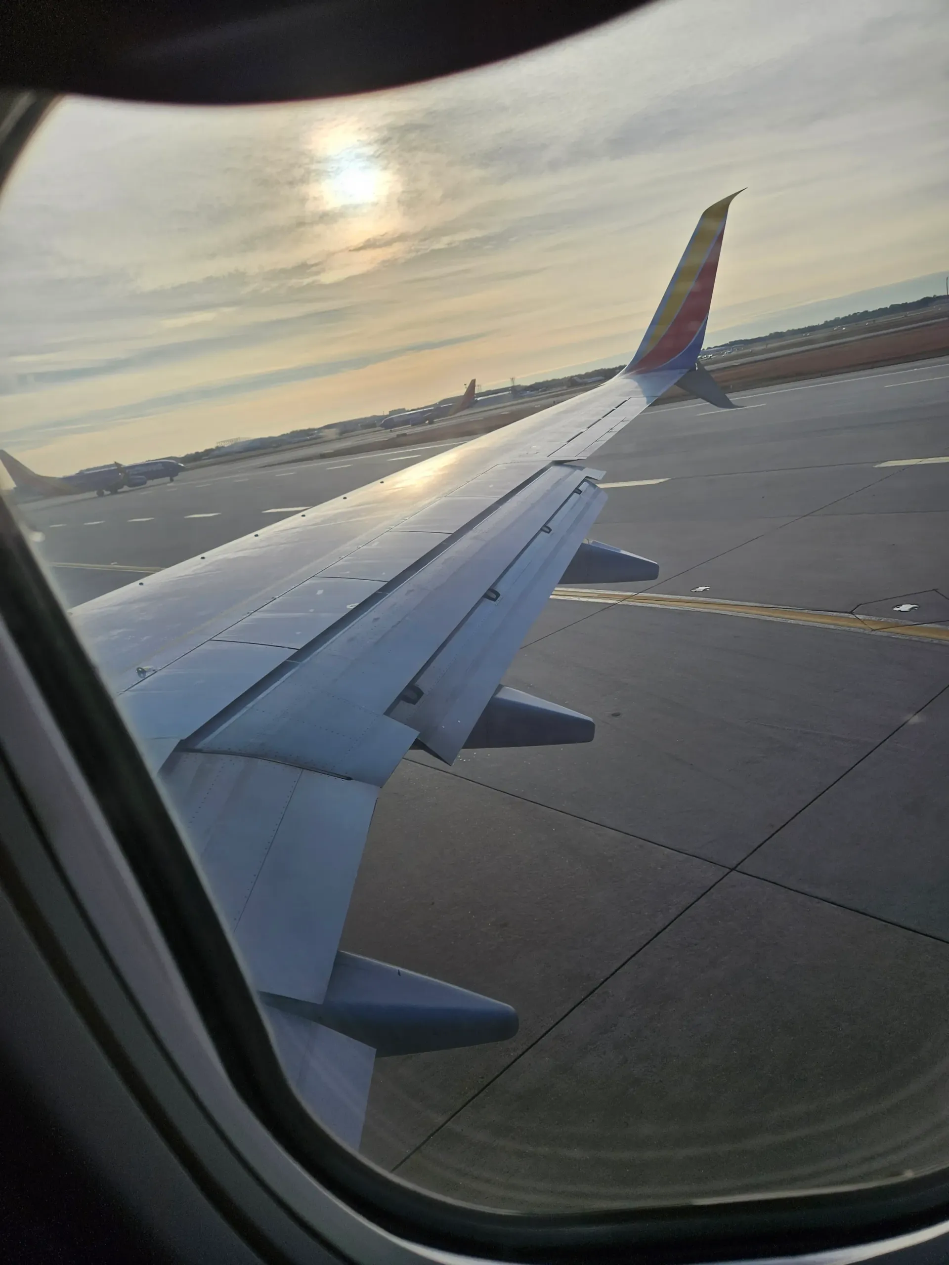 The wing of an airplane is visible through the window of an airplane.