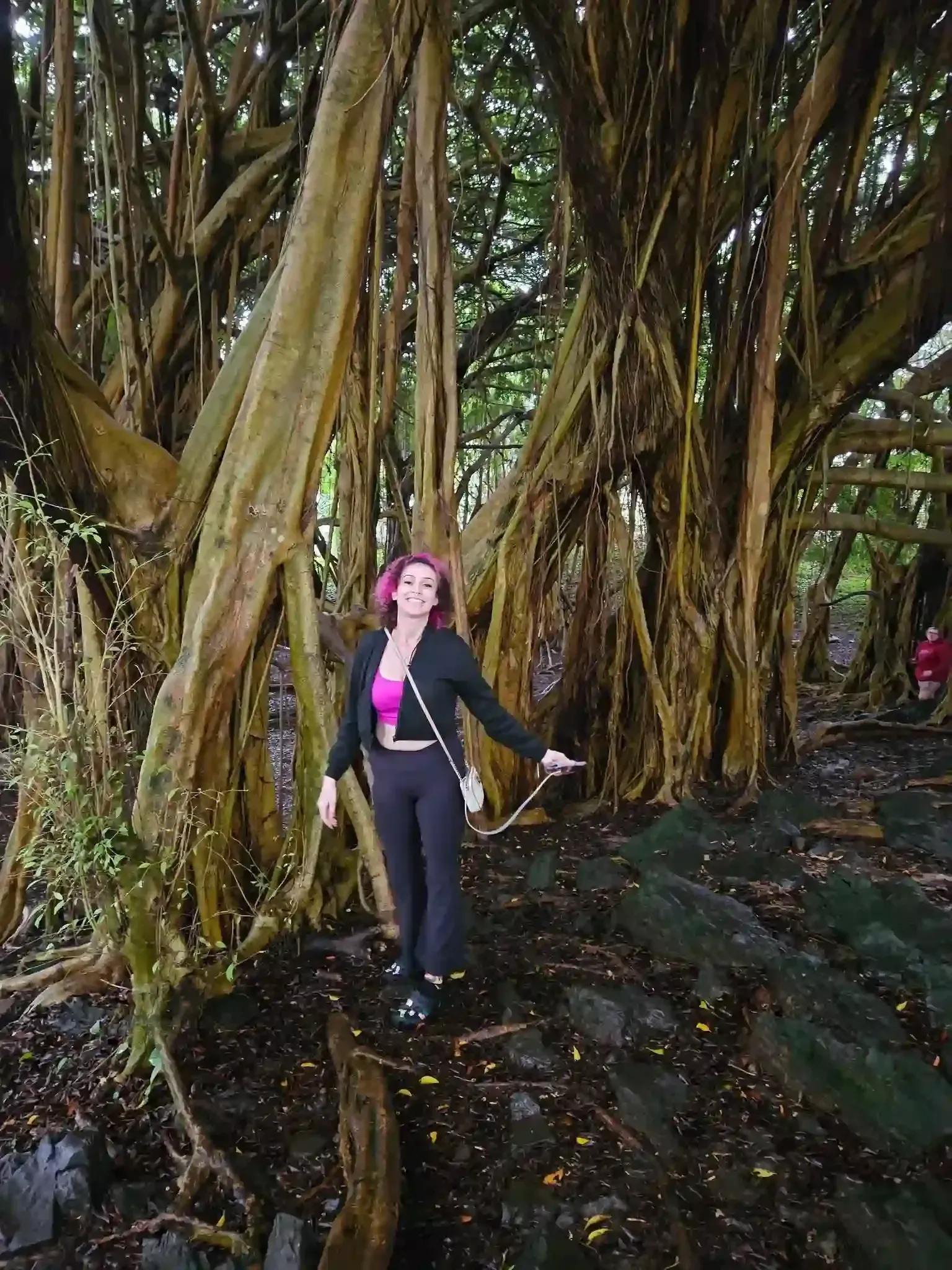 A woman is standing under a tree with lots of branches.
