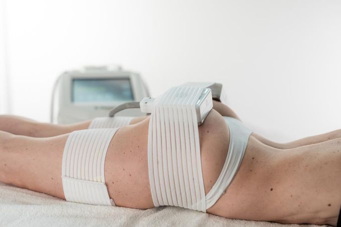 Persona sdraiata su un lettino da trattamento con bende bianche sulla gamba, in un contesto di terapia clinica.