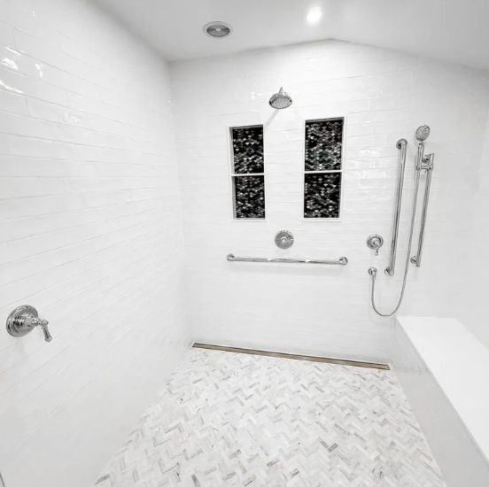 Bright white accessible shower with bench, grab bars, handheld sprayer, and tiled floor
