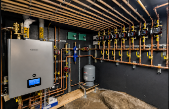 Utility room with wall-mounted boiler, pipes, valves, and a water tank on a concrete floor