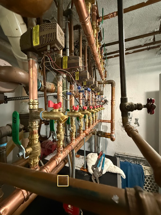 Copper industrial piping and valves in a mechanical room, with gauges and insulated pipes overhead.