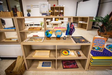 A shelf with a globe on top of it in a classroom.