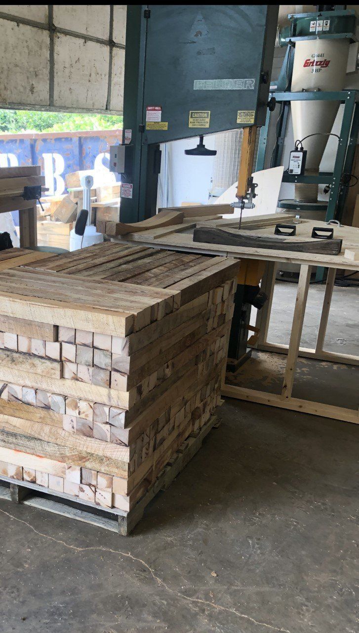 A pallet of wood is sitting in a warehouse next to a machine.