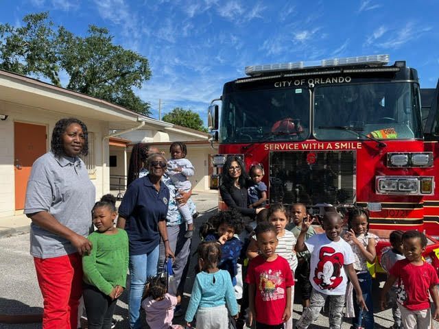 A group of children are standing in front of a fire truck.