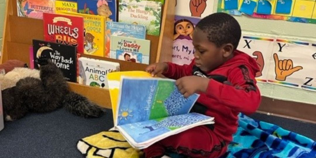A young boy is sitting on the floor reading a book.