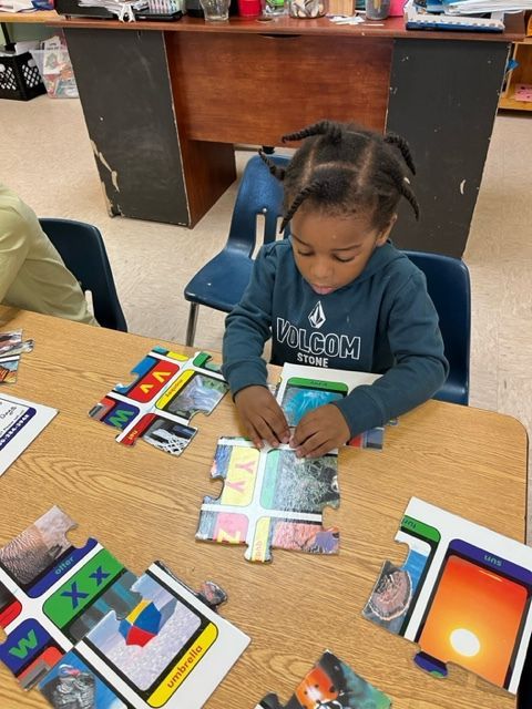 A little girl is sitting at a table playing with puzzles.