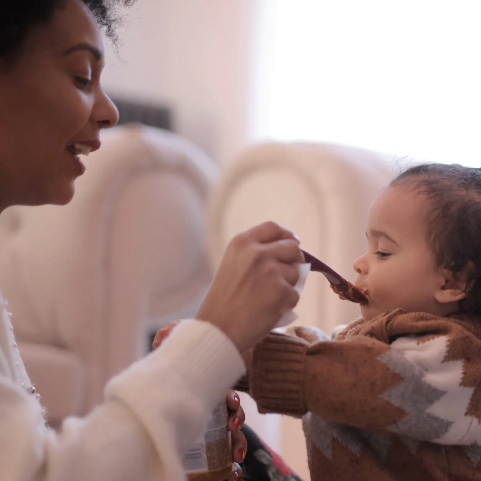 A woman is feeding a baby with a spoon.