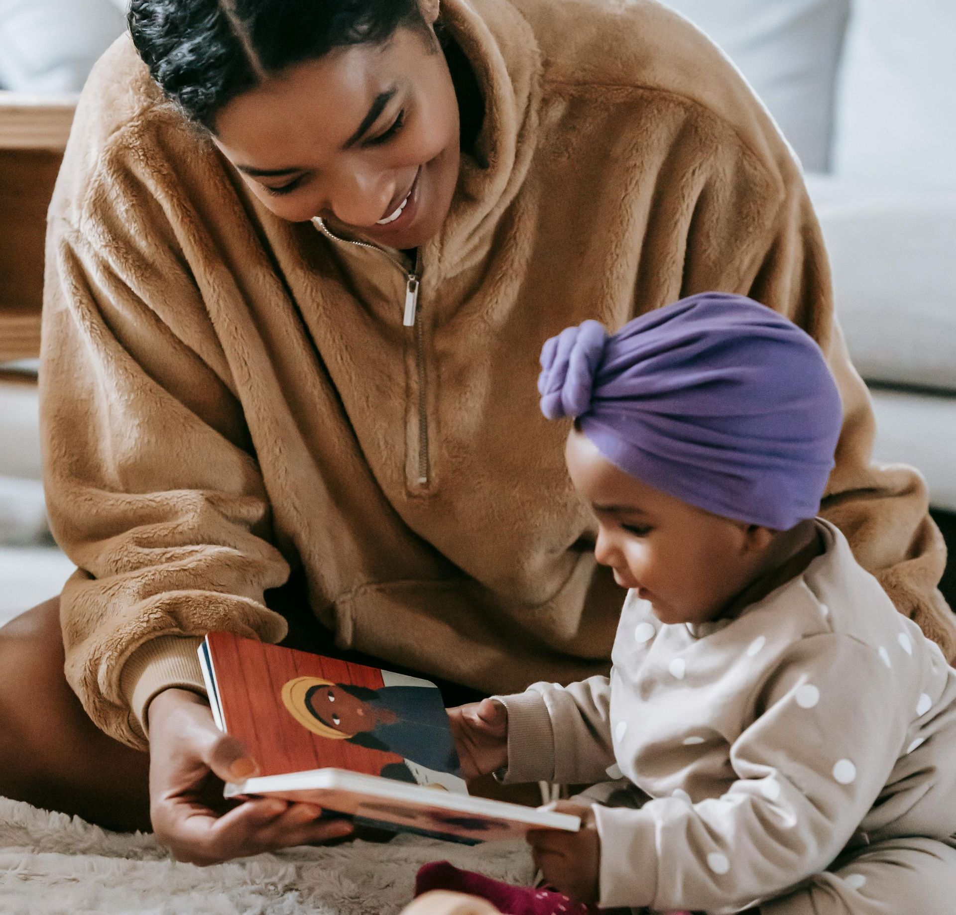 A family is sitting on a couch reading a book together.