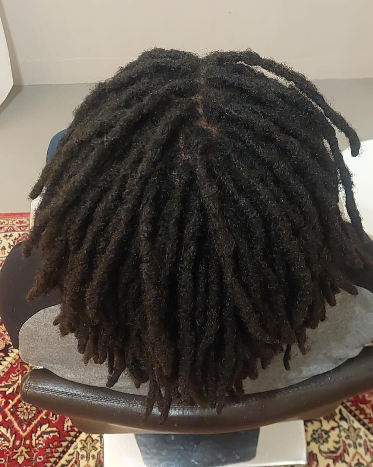 Bovenaanzicht van donkere dreadlocks op het hoofd van een zittende persoon.