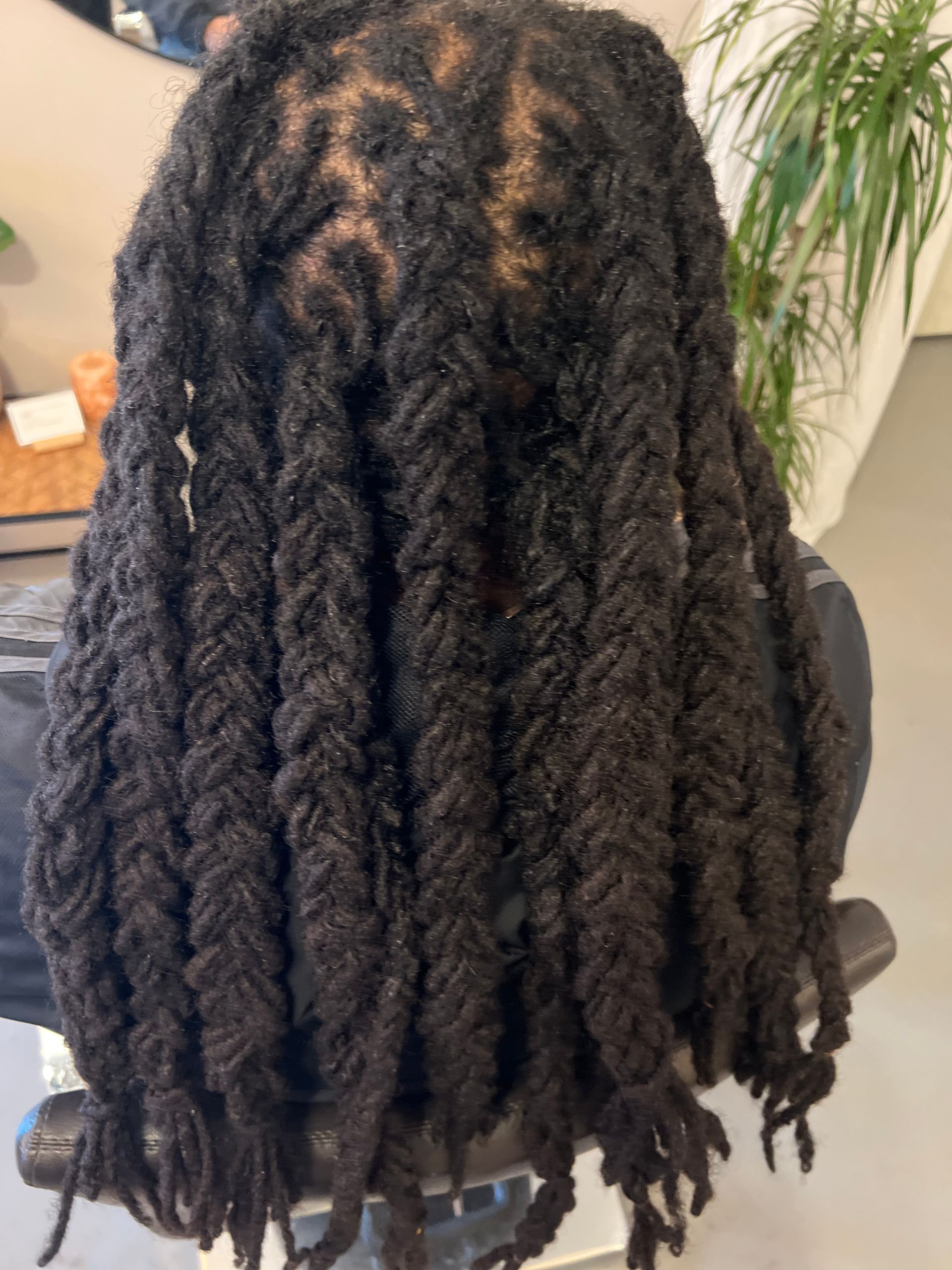 Zwarte dreadlocks in een vlechtachtig patroon, van achteren gezien.