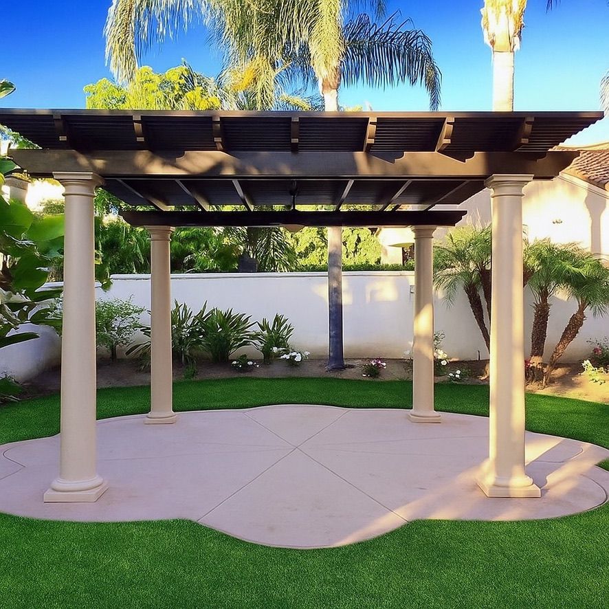 Pergola with dark brown roof, beige columns on a concrete patio, set in a grassy backyard.