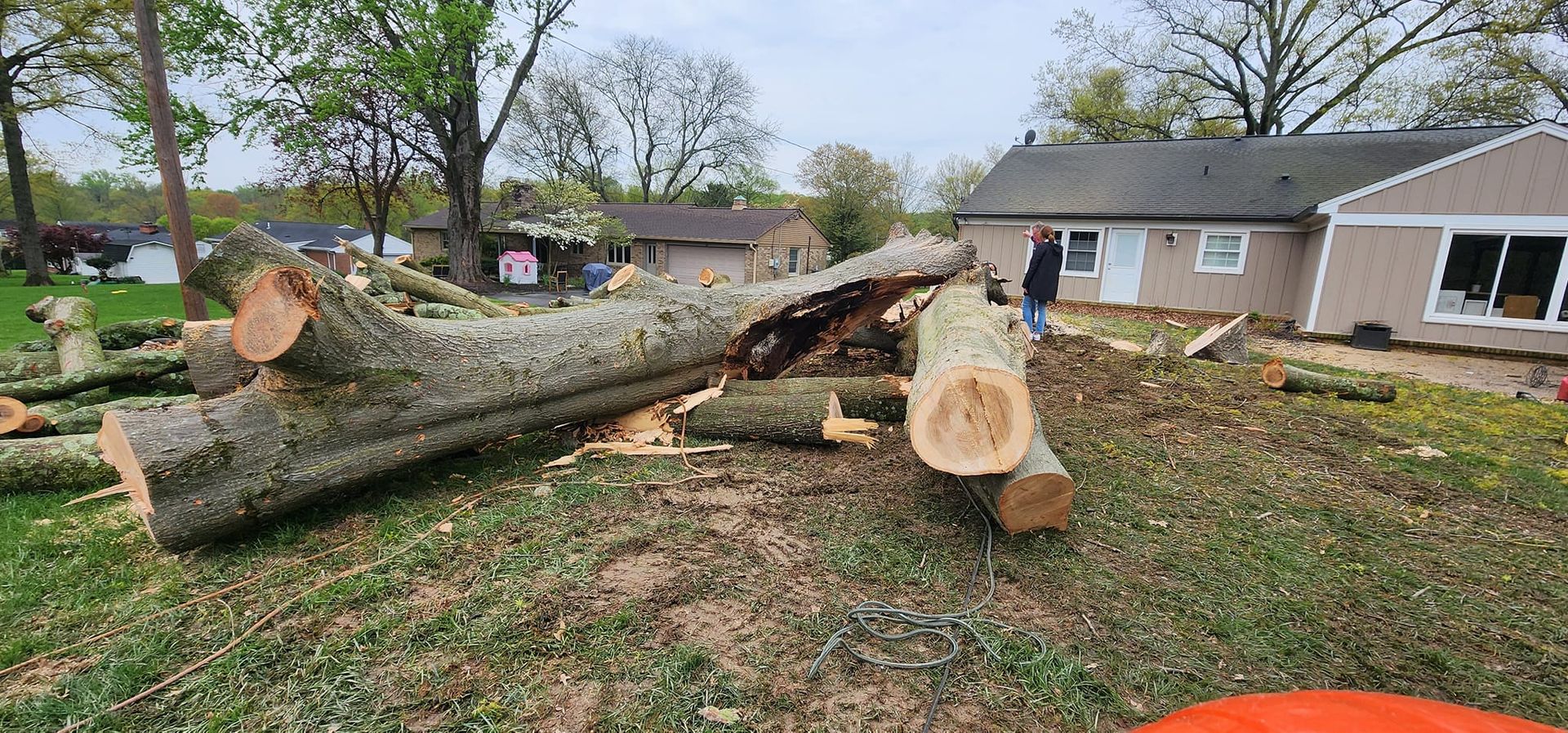A pile of logs laying on the ground in front of a house.