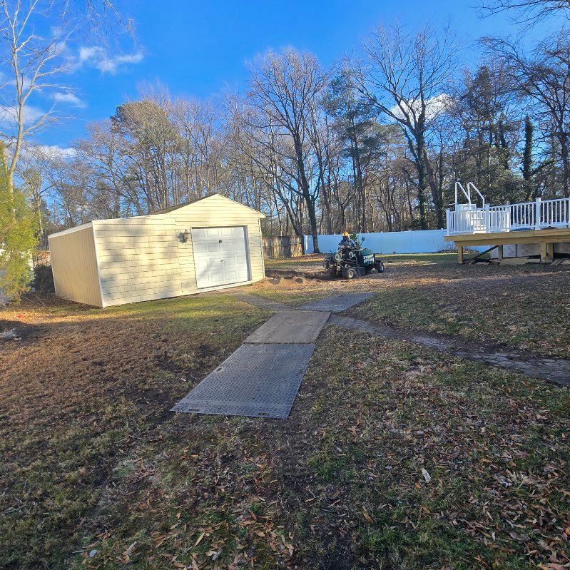 Backyard scene with shed, concrete path, lawn, trees, and a deck with pool.