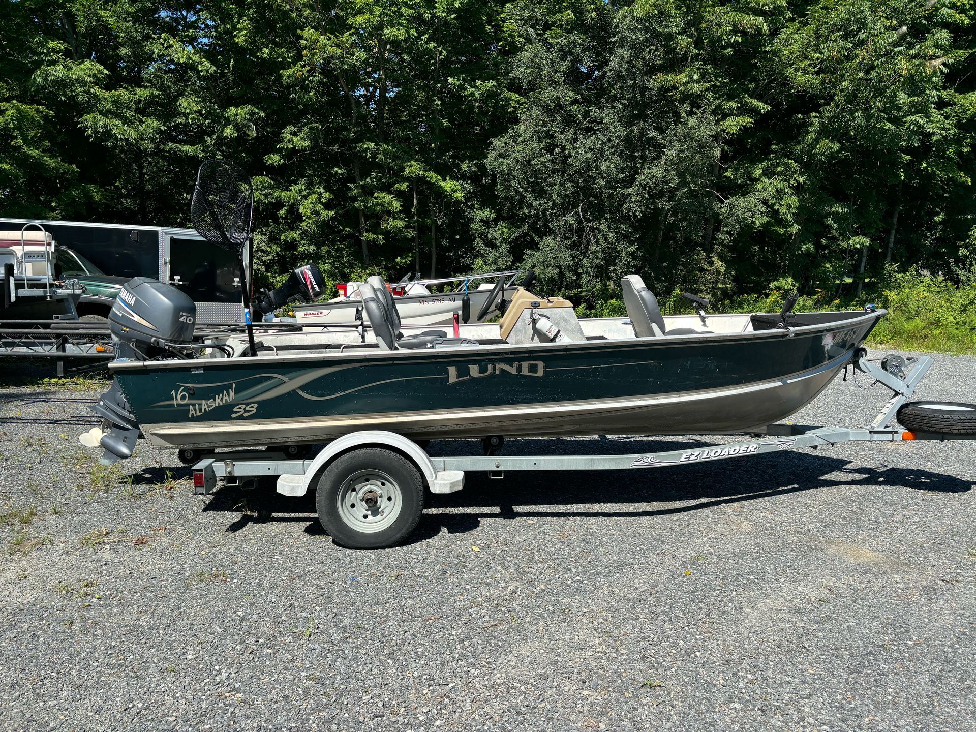 A red and white boat is docked at a dock on a lake.