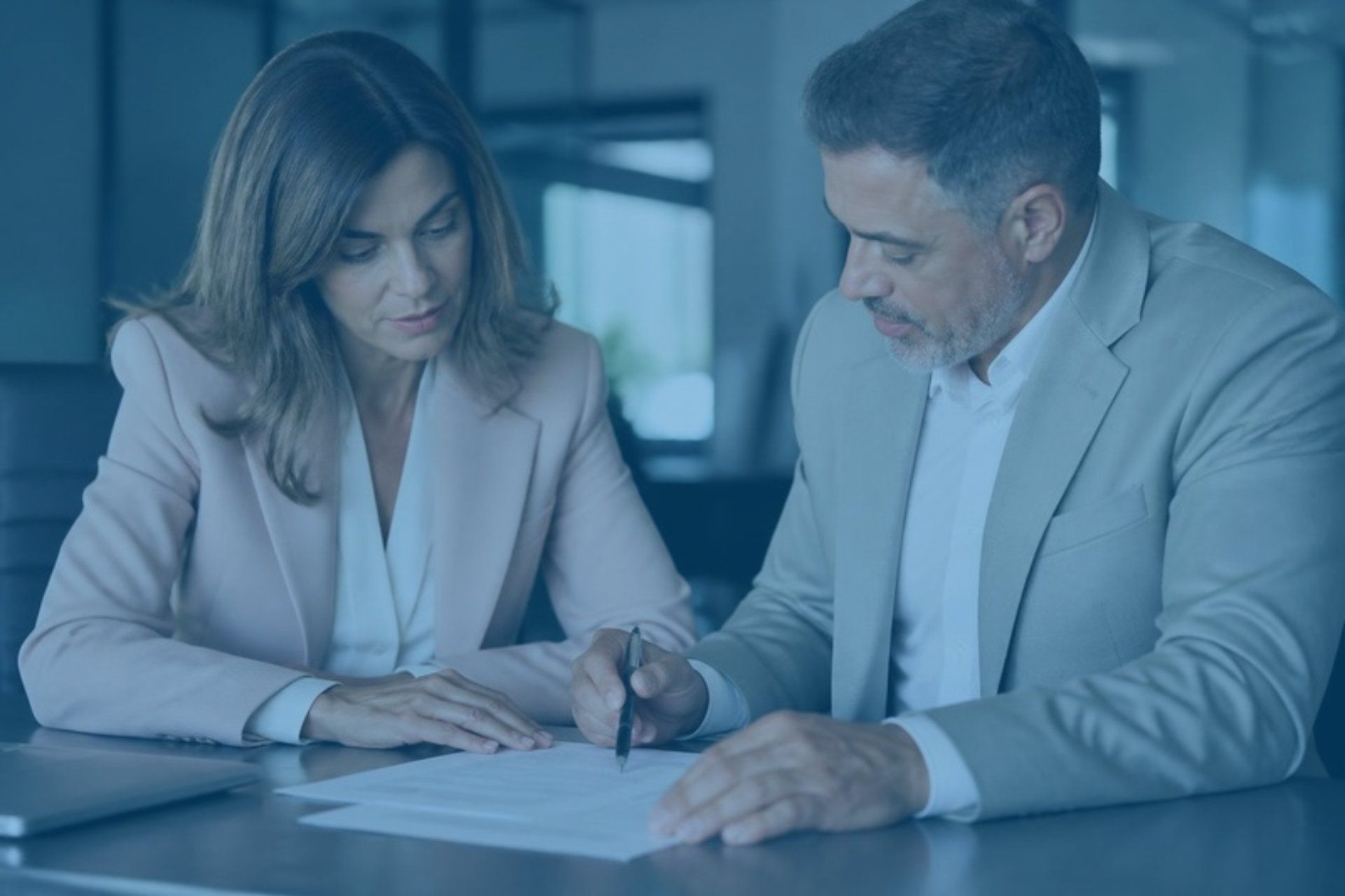 Two business professionals reviewing a printed contract at a conference table
