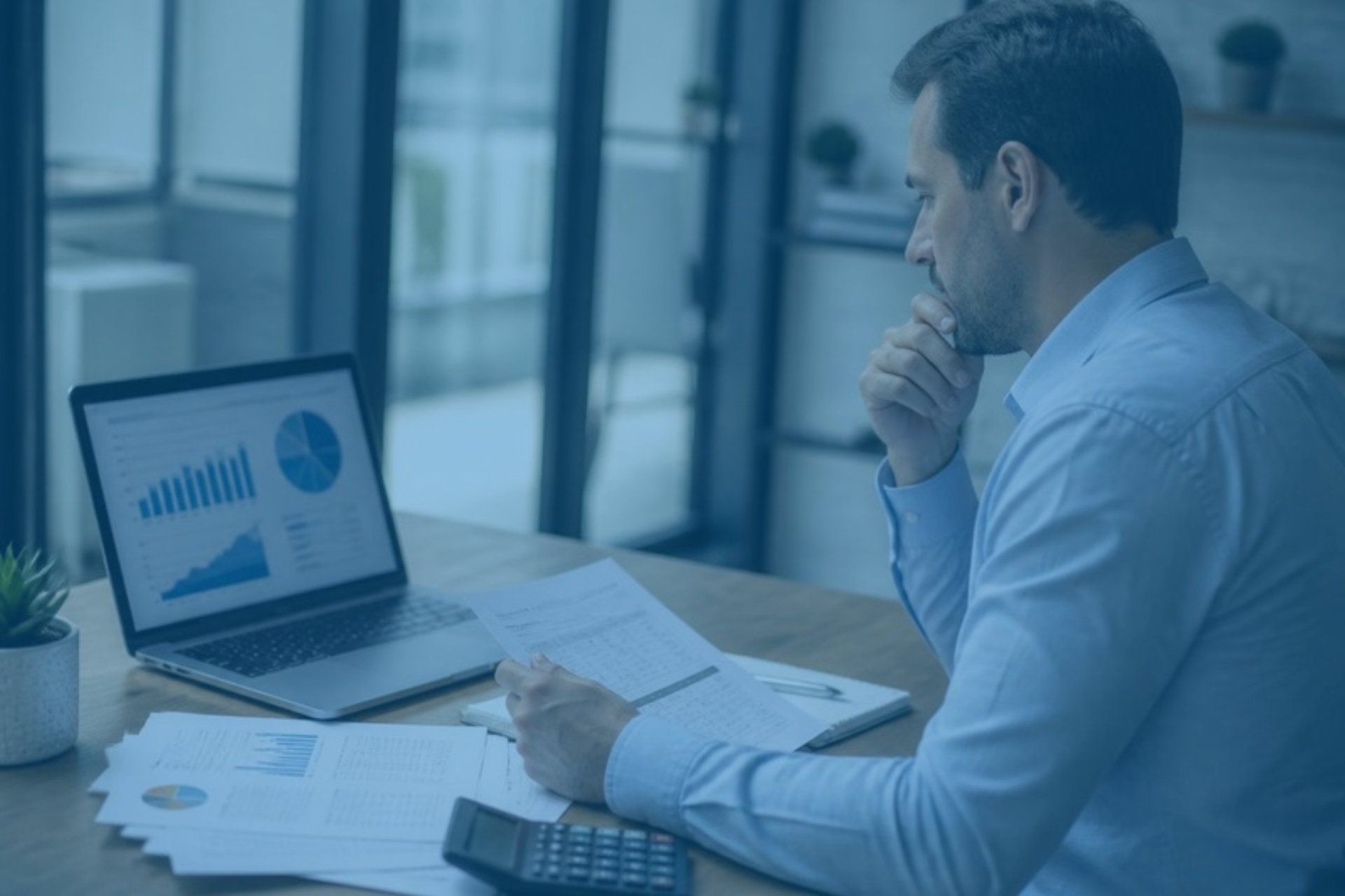 Business owner reviewing valuation charts on a laptop beside printed financial statements