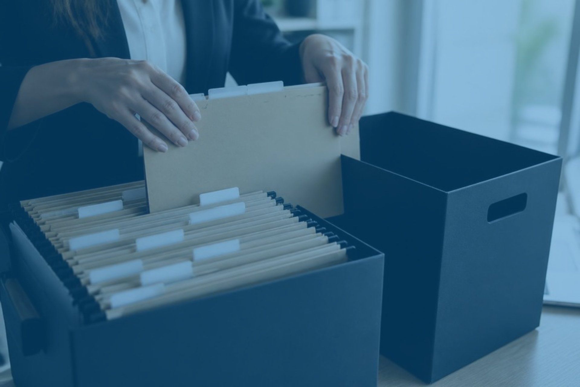 Hands moving labeled file folders from one document box to another
