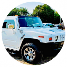White Hummer H2 Limo parked outdoors under a sunny sky, shown in a circular frame.