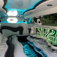Luxury limousine interior with white seats, blue LED lighting, and neon green accents
