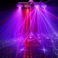 Purple laser beams radiate from a central light fixture across a dark stage