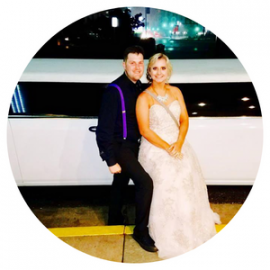 Couple posing beside a white limousine at night, with the woman in a white gown and the man in dark attire.